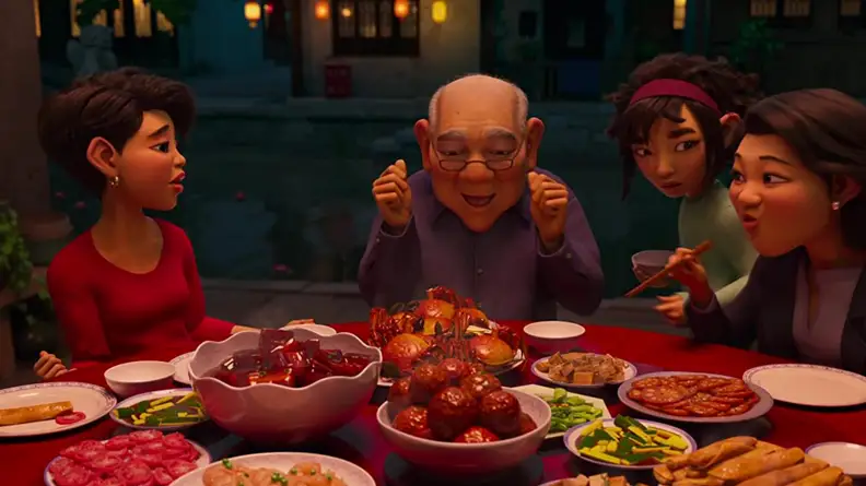 A still from the film Over the Moon featuring the main character and her family around a table, eating a meal.