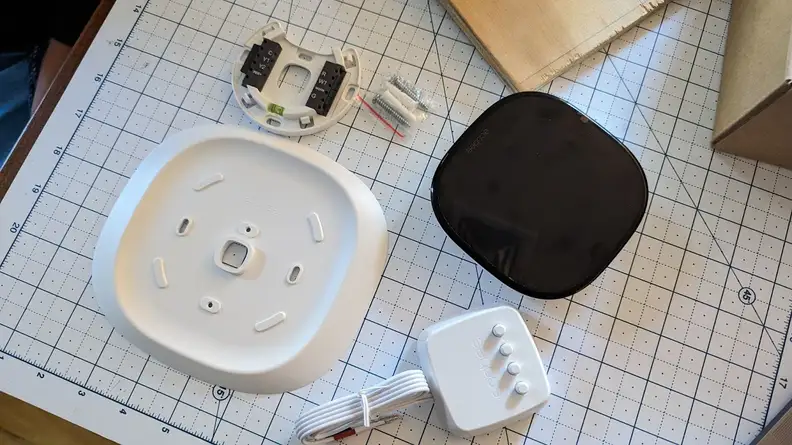 A disassembled Ecobee Smart Thermostat Enhanced sits on a ruler board.