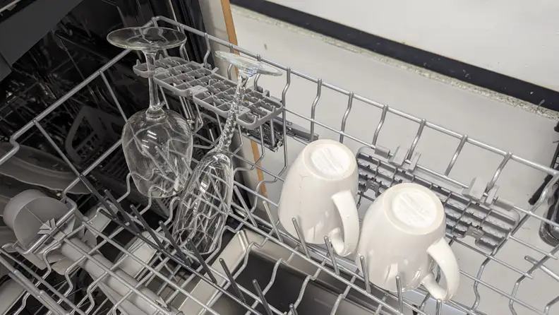 A close-up of the dishwasher's middle rack. It's holding a few coffee mugs and some stemmed glasses, which are secured by the stemware holsters.