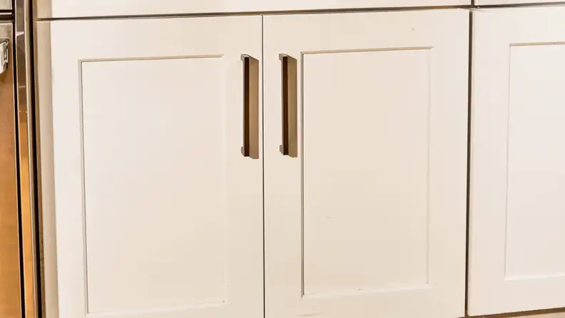 A gif of a person opening cabinet doors and Caraway cookware is stored inside the cabinet.