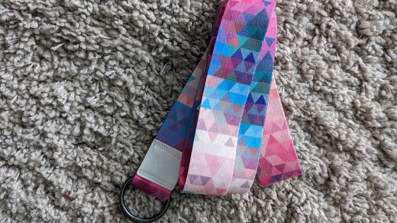Yoga Design Lab Strap resting on a carpeted floor