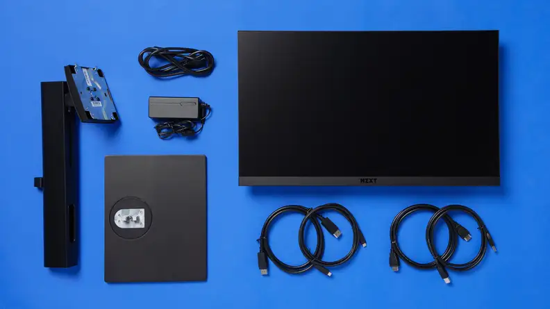 The NZXT Canvas 25F and its contents, including the monitor stand, AC plug and some cables.