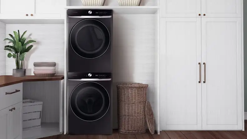 Black washer-dryer combo next to white cabinets