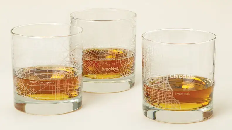 Three glasses with map design filled with amber colored liquid