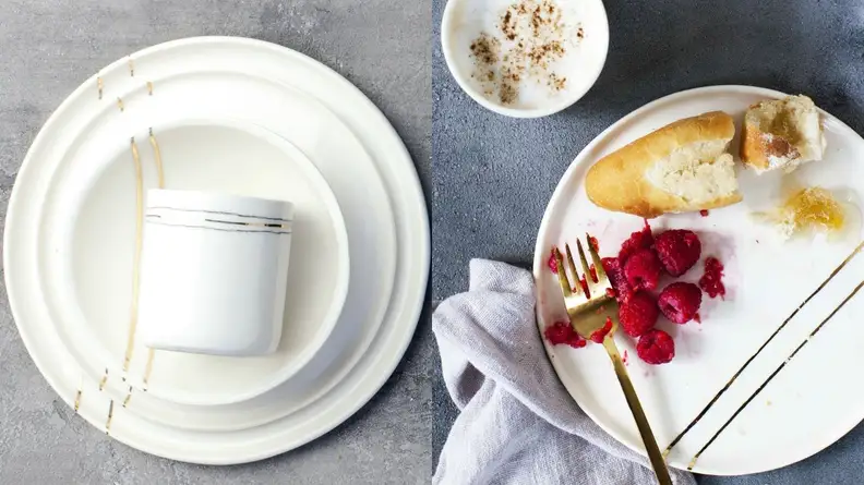 White plates with two gold lines stacked and at a place setting with bread and raspberries.