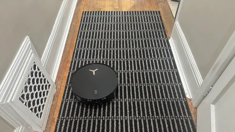A black robot vacuum in a hallway