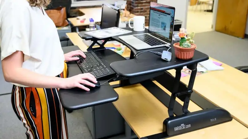 Close-up of a person working on a laptop at the VariDesk Pro Plus standing desk.