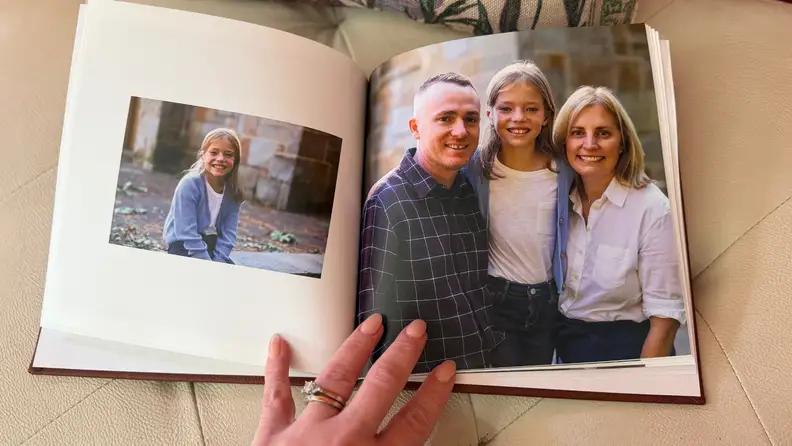 a hand holds open a photo album