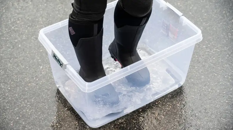 Girl stomps in place in a tub of water wearing Muck Arctic Ice Tall boots.