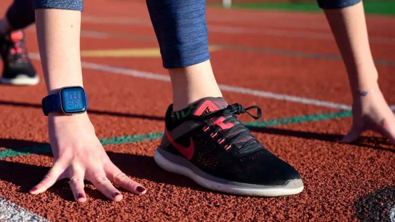 A tight shot of a person wearing Nike running shoes on a track.