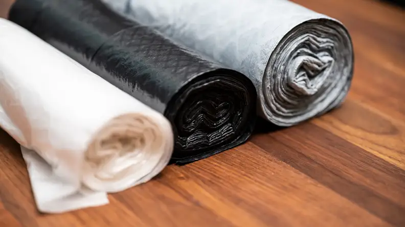 Three rolled up trash bags in a row.