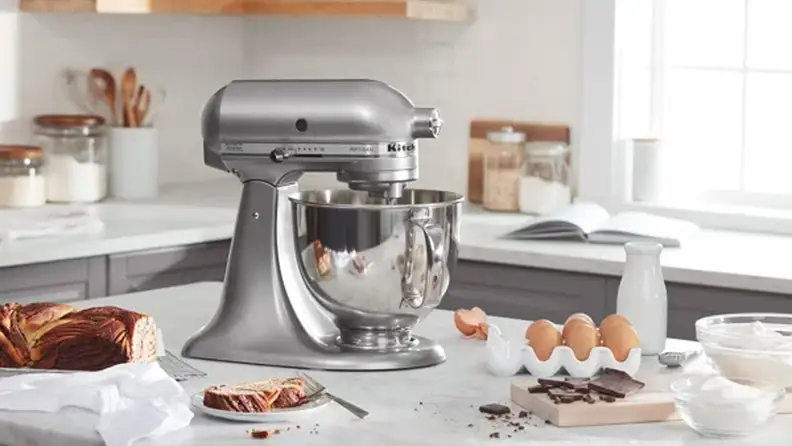 A KitchenAid Five-Quart Artisan Series Tilt-Head stand mixer being used in a kitchen.