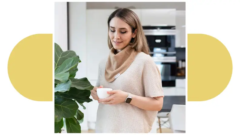 A person wearing a Drybble bib around their neck while scrolling on a smartphone.