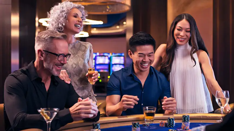 Four people and a dealer playing a table game at a casino