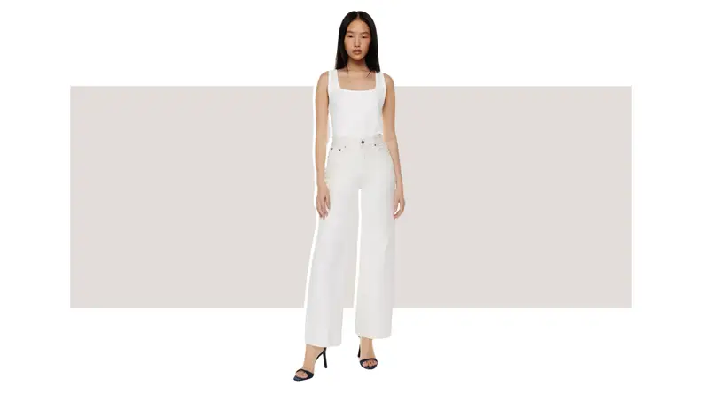 A model wearing a pair of white high-waisted wide-leg jeans.