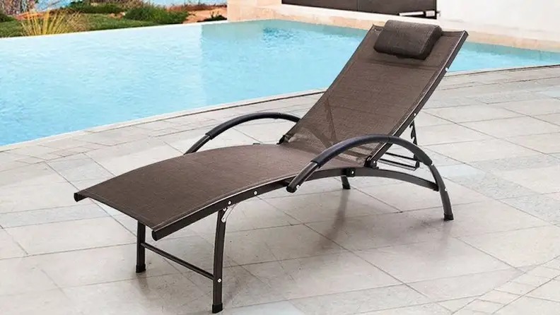 A deck chair besides a swimming pool.