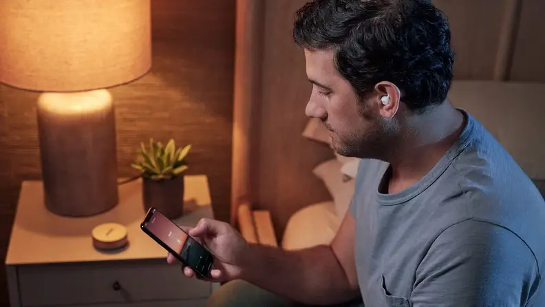 a man with the Bose Sleepbuds II in controls them from his phone