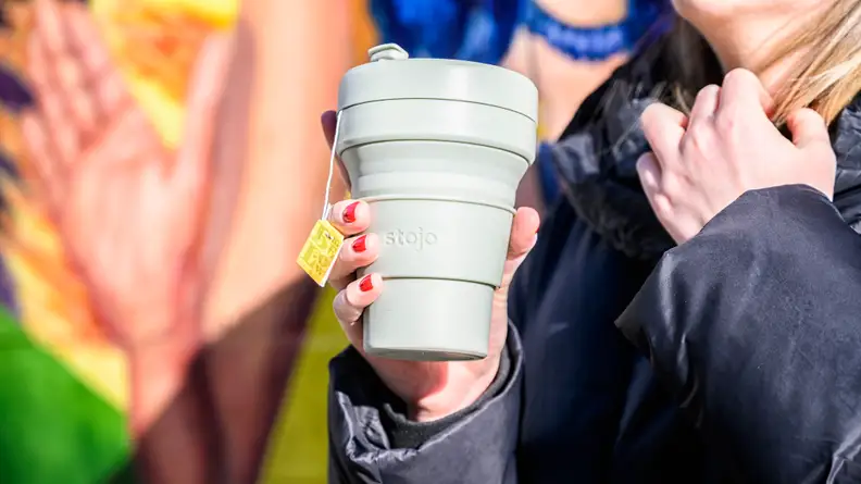 A photo of a woman holding the Stojo Cup.