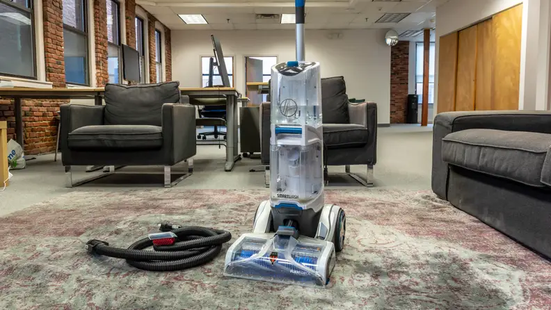 Carpet cleaner on a rug next to cleaning accessories