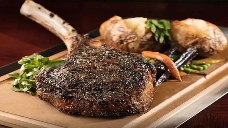 Bone in steak cooked well done plus sides, all on a wooden board