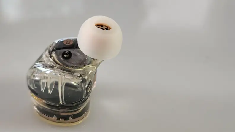 A single earbud sits, with its driver up.