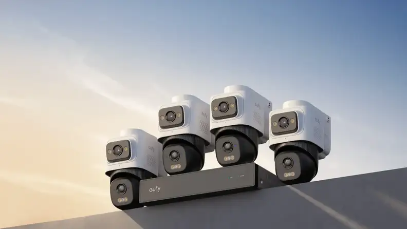 A group of four security cameras, with sky behind them