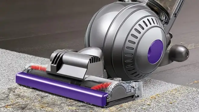 Purple and silver Dyson vacuum on gray carpet