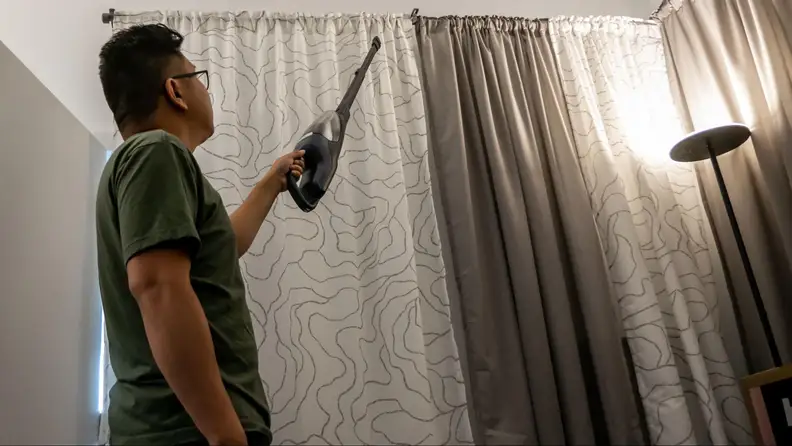 Person holding Electrolux Well Q7 handheld with telescopic wand.