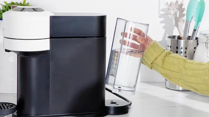 Person placing water reservoir chamber back into place on the back of the Nespresso Vertuo Next coffee maker.