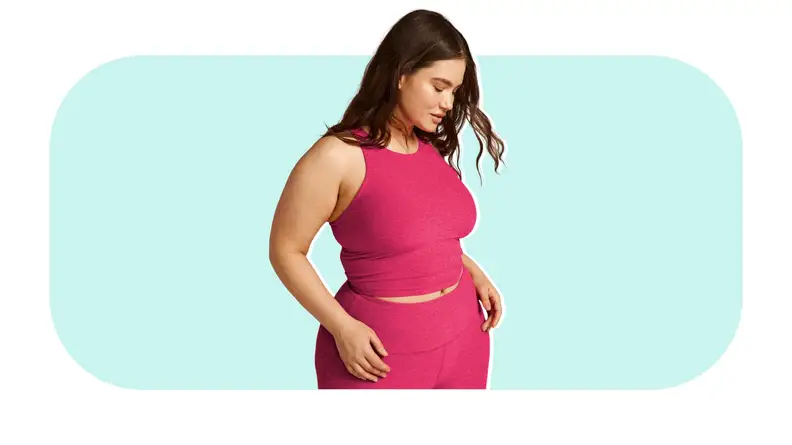 Model posing while wearing pink Beyond Yoga Refocus Cropped Tank and pants.