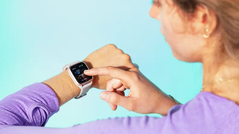 A person taps a Garmin Venu Sq 2 fitness tracker on their wrist.