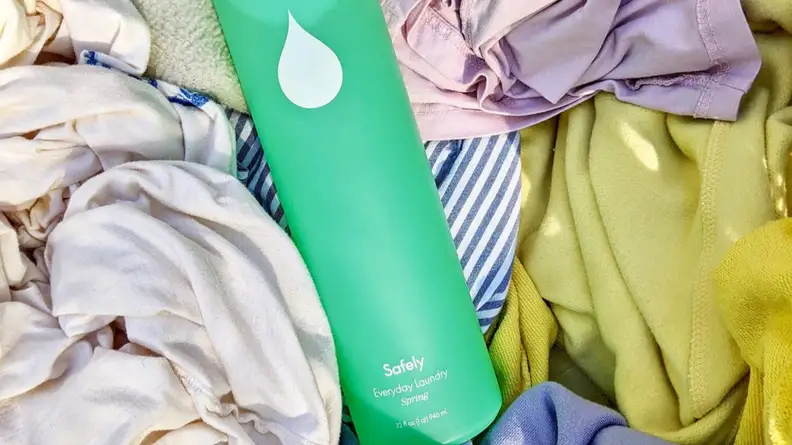 Bottle of detergent surrounded by clothes.