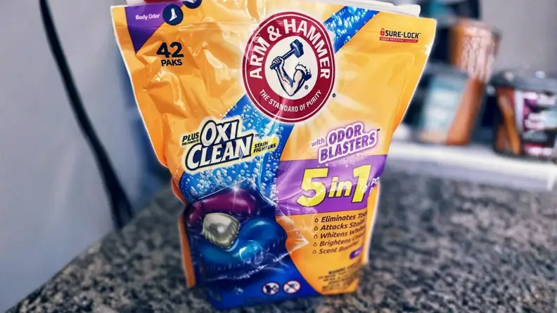 A bag of Arm & Hammer Plus OxiClean 5-in-1 laundry paks sits on a kitchen counter.