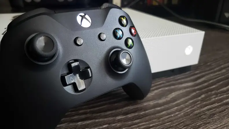 An Xbox controller sitting on a table next to an Xbox console