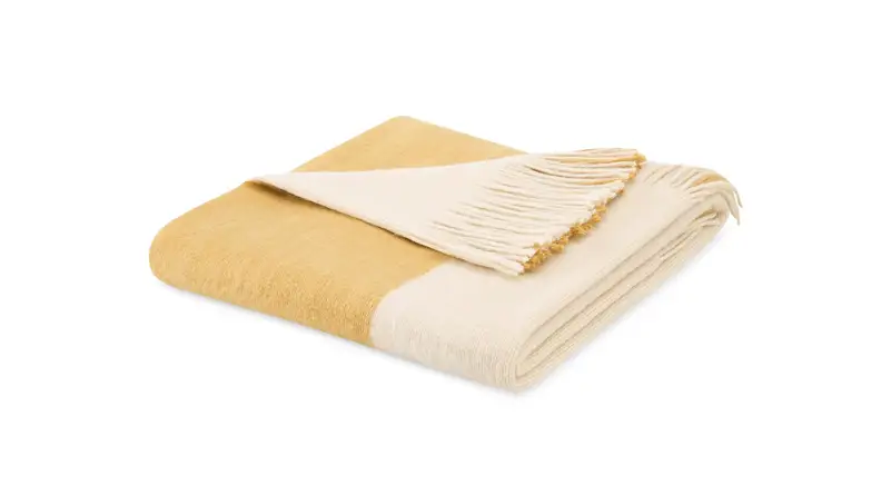 An image of a colorblocked white and gold blanket folded.