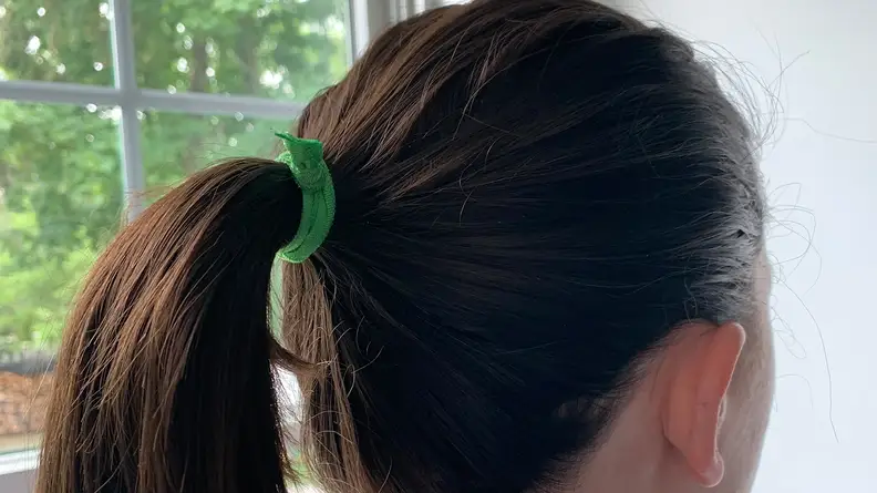 A person with long brunette hair wearing the 79 Style 100 Hair Tie in her hair for a ponytail.