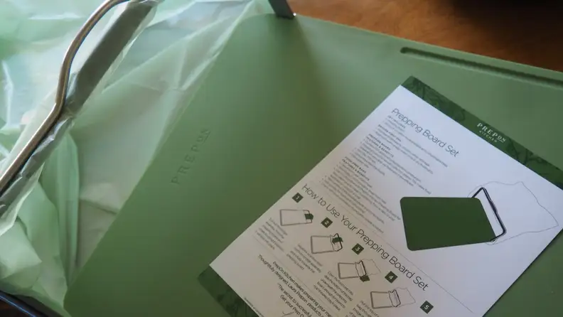 Green chopping board with compost bag attached to its edge