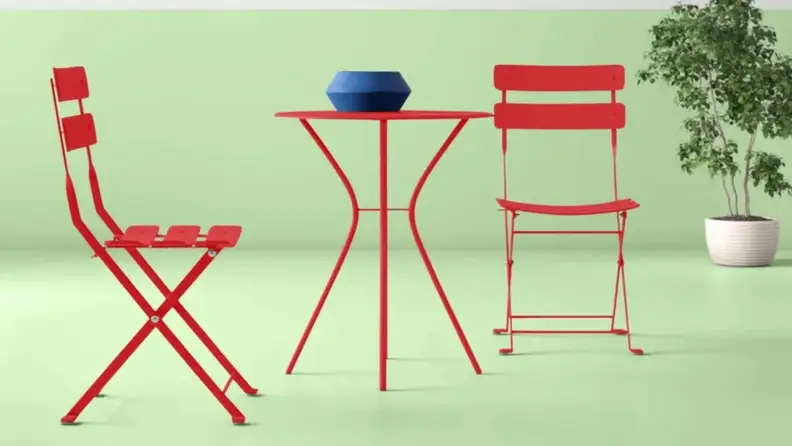 Red outdoor bistro dining set against green background.