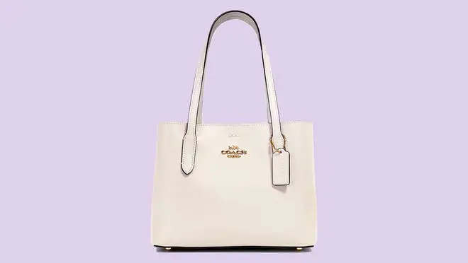 A white Coach handbag against a purple background.