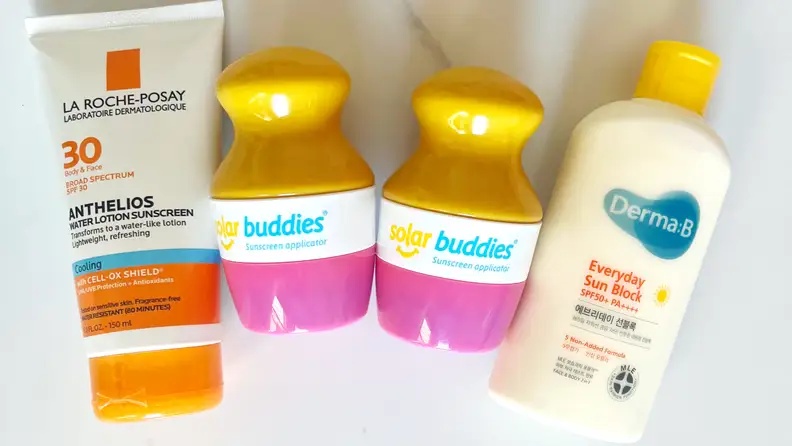 Different sunscreens next to two Solar Buddies Sunscreen Applicators.