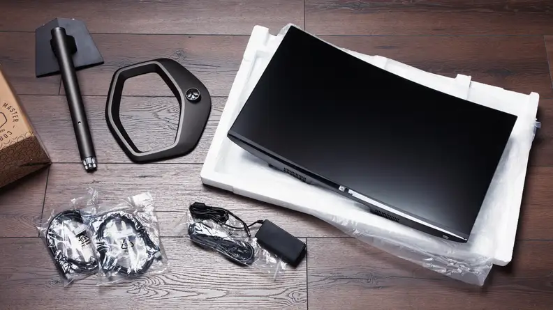 An unassembled gaming monitor with all its parts neatly placed next to each other on the floor.
