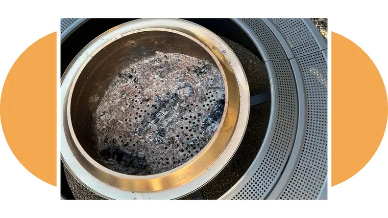 The ashes of a dead fire sit in the center of a Solo Stove Surround, in an image that highlights the tabletop.