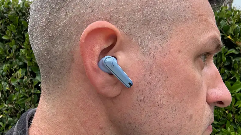 A close shot of the blue Anker Soundcore Liberty 4 NC earbud in a man's ear.