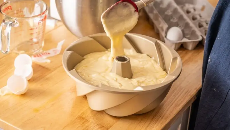 A person mixes batter in a cake pan.