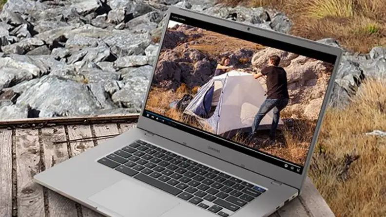 A laptop sits on top of a rock outside.