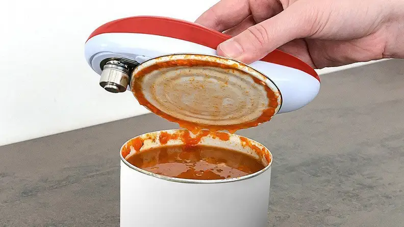 Hand opening a can with an automatic can opener