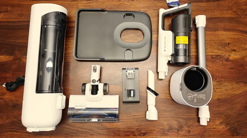 Separated vacuum parts lay on a brown wooden floor