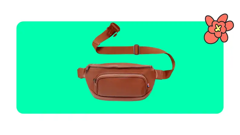 A tan faux leather Kibou fanny pack with extended strap in front of a green background with a red cartoon flower in the corner.