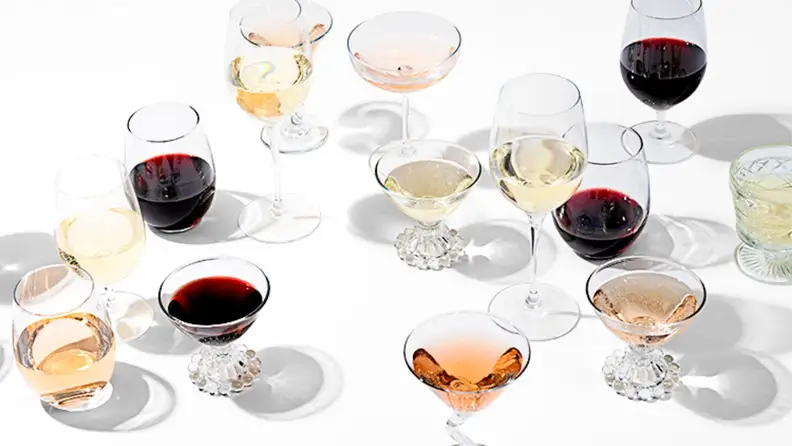 A variety of wines poured in a variety of glass shapes shot on a white background.