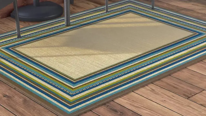 Blue and green multi-colored outdoor rug on ground.